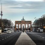 Brandenburger Tor in Berlin mit Straßen und Fahrzeugen im Vordergrund.