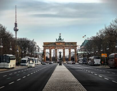 Brandenburger Tor in Berlin mit Straßen und Fahrzeugen im Vordergrund.