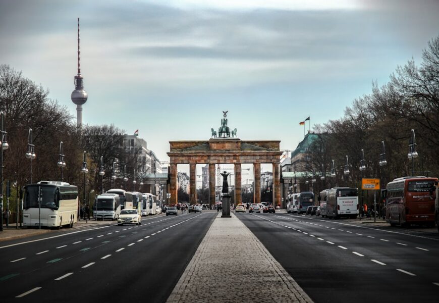 Brandenburger Tor in Berlin mit Straßen und Fahrzeugen im Vordergrund.