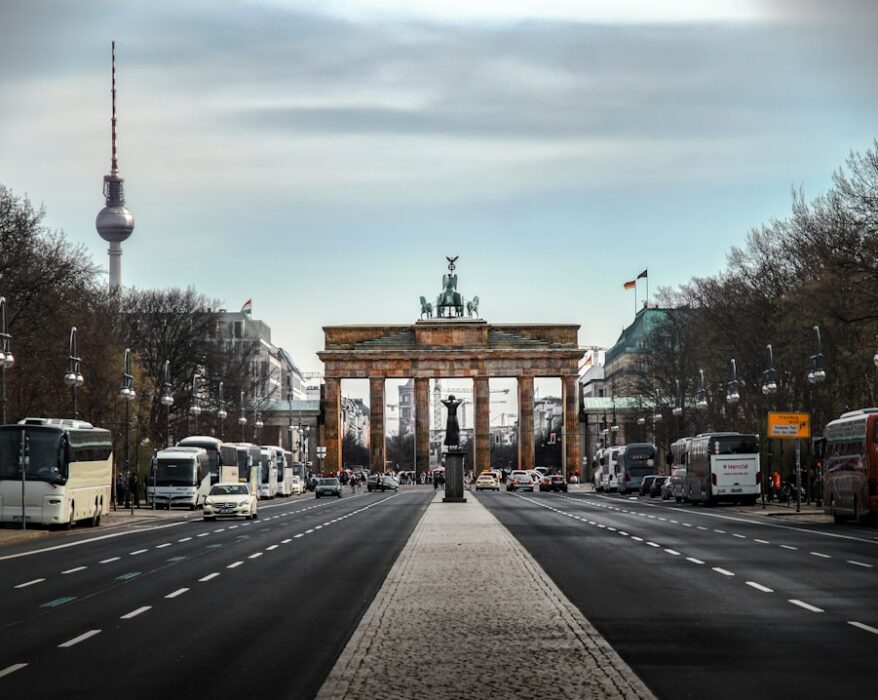 Brandenburger Tor in Berlin mit Straßen und Fahrzeugen im Vordergrund.