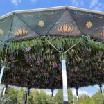 Pavillon mit einem dekorativen Dach und hängenden Pflanzen und Blumen in verschiedenen Farben.