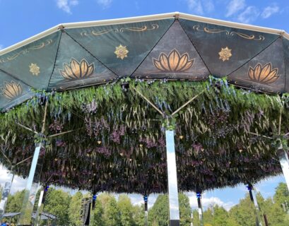 Pavillon mit einem dekorativen Dach und hängenden Pflanzen und Blumen in verschiedenen Farben.