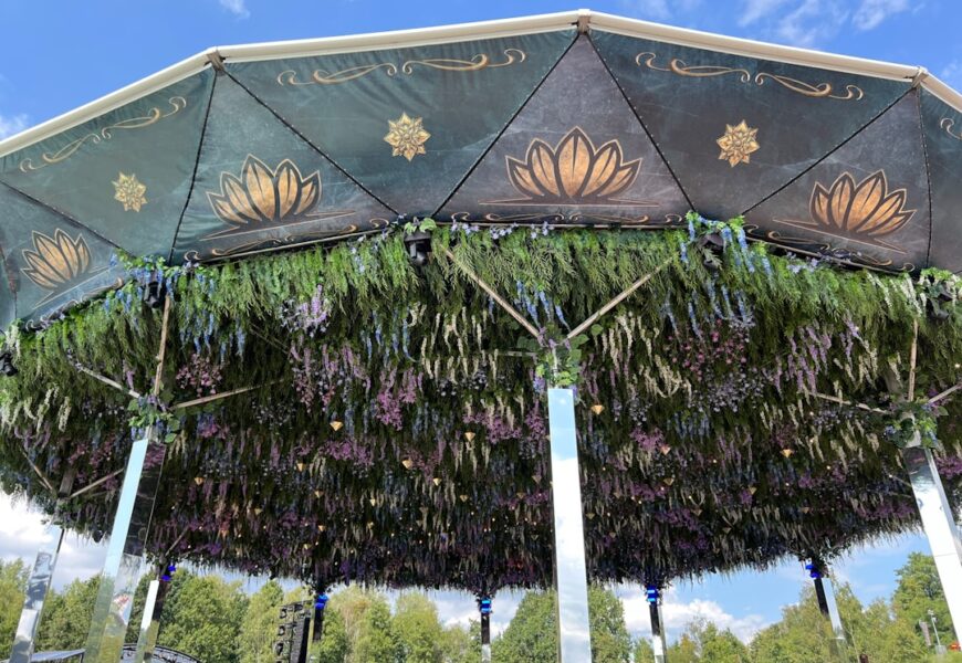 Pavillon mit einem dekorativen Dach und hängenden Pflanzen und Blumen in verschiedenen Farben.