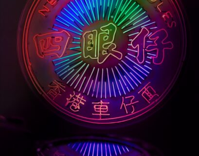 Neon-Schild mit dem Schriftzug 'Nerdy Noodles' in bunten Farben und reflektierender Oberfläche.