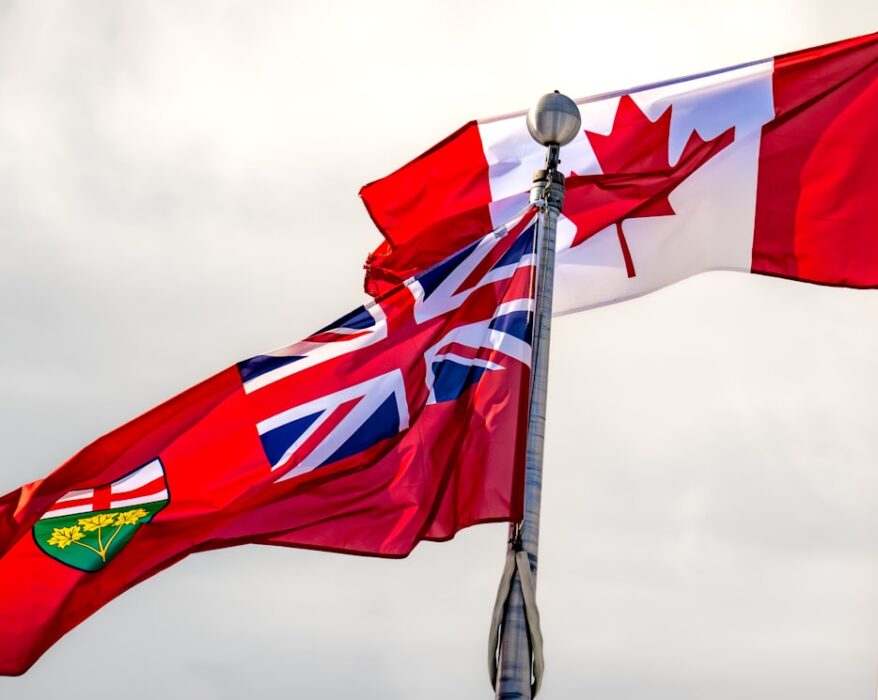 Die kanadische Flagge und die Flagge von Ontario wehen im Wind an einem Flaggenmast.
