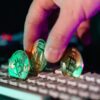 Eine Hand platziert drei Kryptowährungs-Münzen auf einer Computer-Tastatur.