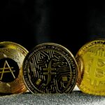 Drei goldene Kryptowährungs-Münzen mit Symbolen für verschiedene digitale Währungen.