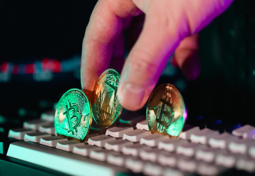 Eine Hand platziert drei Kryptowährungs-Münzen auf einer Computer-Tastatur.